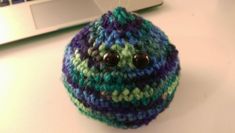 blue and green crochet ball with black eyes attached