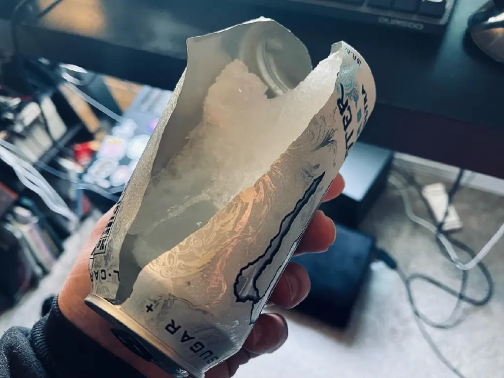 Can of Monster energy drink split open top to bottom with a block of ice inside where one might expect liquid.