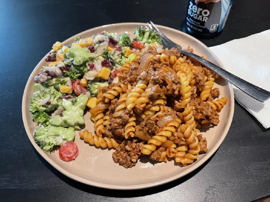 Broccoli salad and spiral noodles with ground beef and sautéed onions
