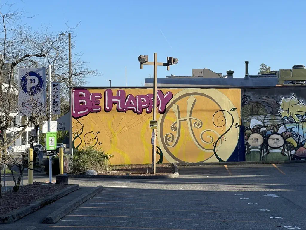A brightly colored mural reads “be happy”