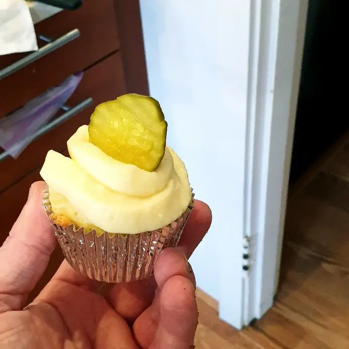 cupcake with a pickle placed on the frosting