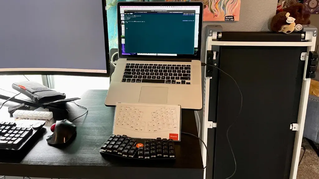 2015 MacBook Pro on a laptop stand, with the funky-looking Atreus keyboard from KeyboardIO and a reference card in front of it.
