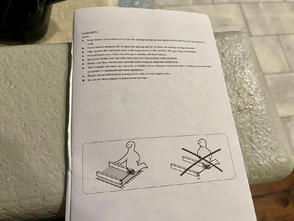 Confusing cautionary cartoon accompanying a list of precautions for assembling an adjustable sit-stand desk.