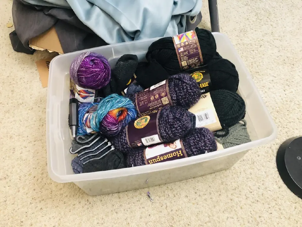 Crate containing yarn, socks, and an electric nosehair trimmer. 