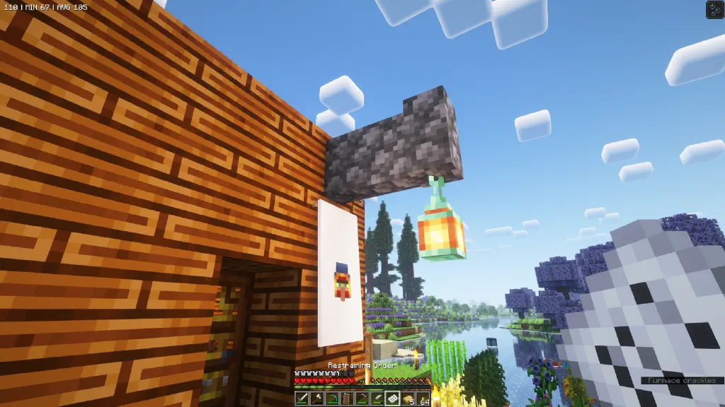 Next to the door of a Minecraft house, a copper lantern illuminates a banner with an image of the wandering trader’s face; the player is holding a piece of paper note, with inventory help text indicating this paper is a restraining order