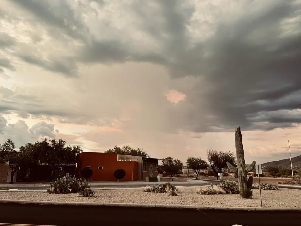 Ominous orange hole in a dark cloud over a small school building with a “be kind” mosaic