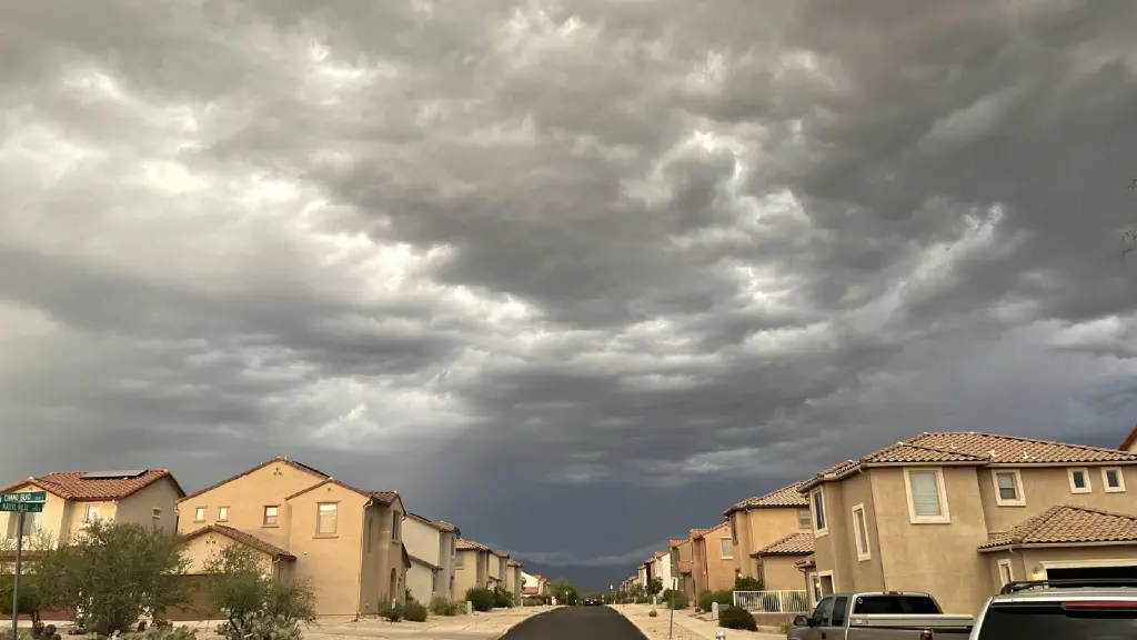 Row houses along a straight road under dark and heavy storm clouds