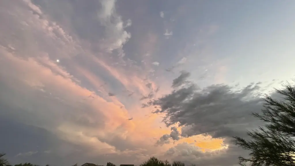 Overlapping clouds. In a riot of grey orange and peach colors, with the half moon visible as a bright point 