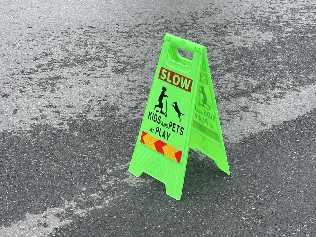 Curb sign reading “SLOW KIDS and PETS at PLAY”
