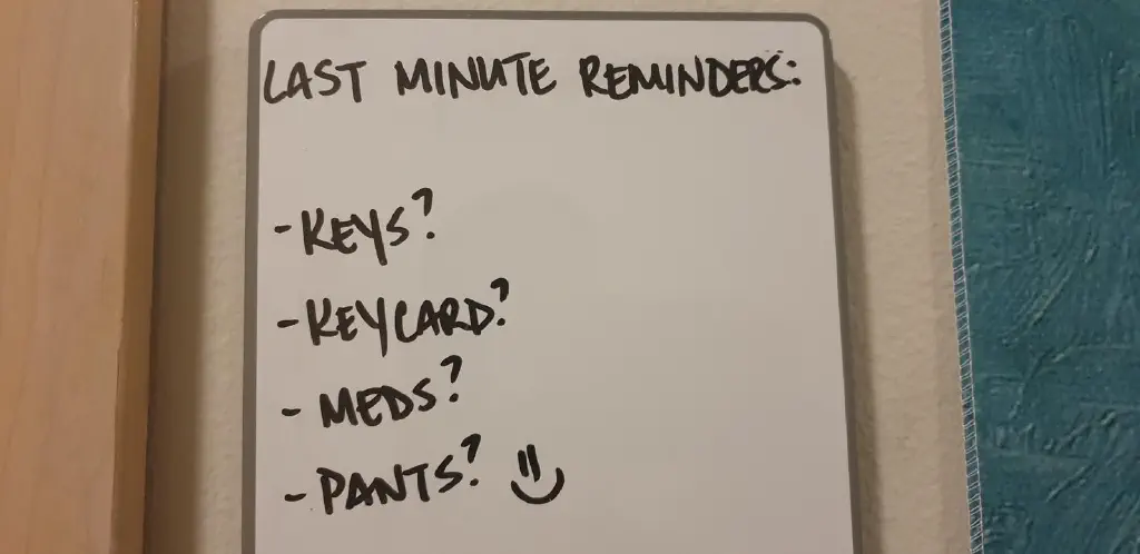 Whiteboard listing &ldquo;last minute reminders: keys? Keycard? Meds? Pants?&rdquo;