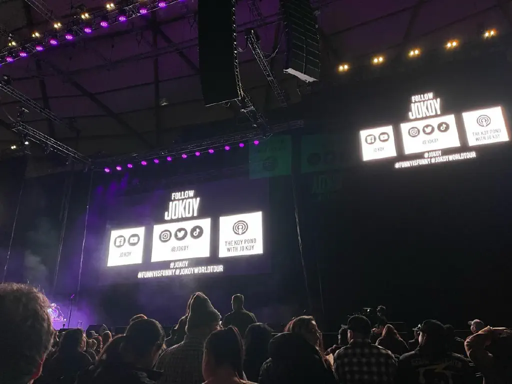 Crowd view of Jo Koy social media signage in a crowded theater 