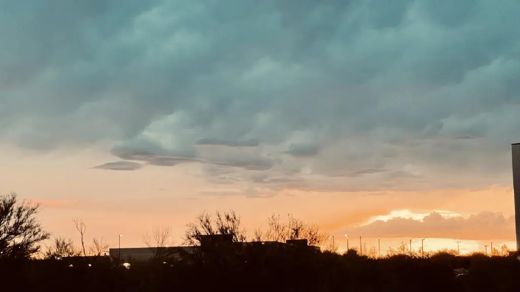 Large ominous cloud overhanging with dark patches, and setting sun behind lower clouds in the distance