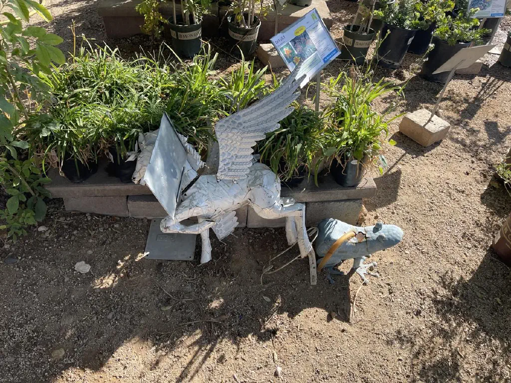Metal frog and Pegasus statues resting near a plant nursery display