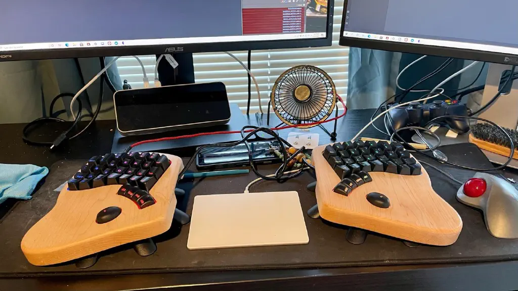 KeyboardIO Model 01 split keyboard with Magic Trackpad in between, trackball to the right, and game controller in the background