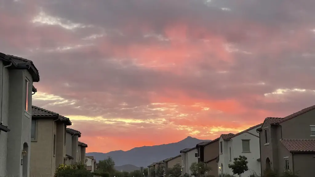 Clouds over a mountain, lit up orange and violet by the sunrise.