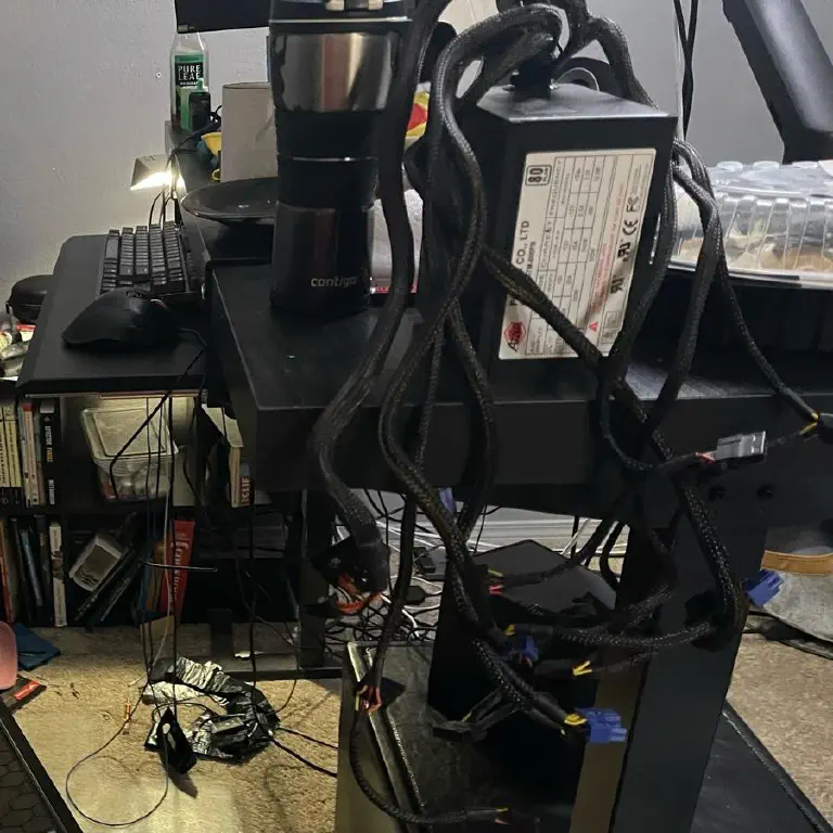 A computer power supply on a desk, cables dangling loose in a serpentine mess
