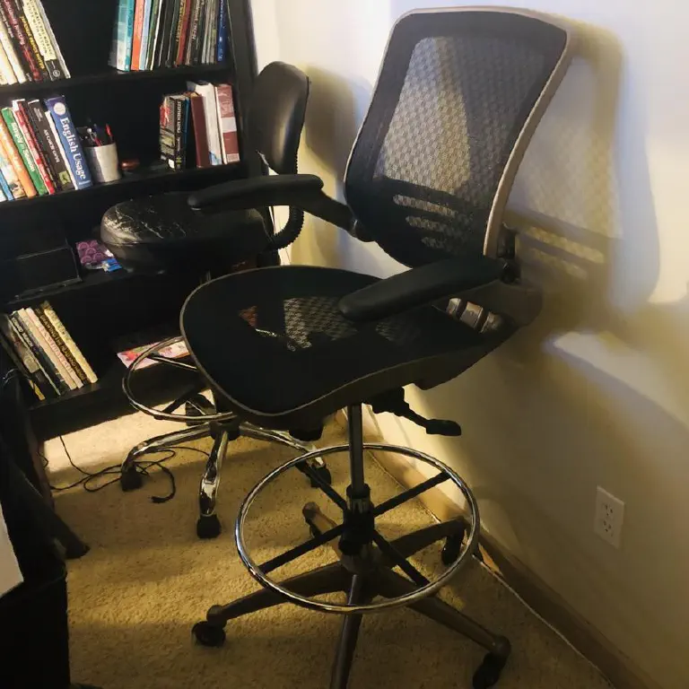 Drafting chair with arms, next to a rather worn drafting chair with no arms. 