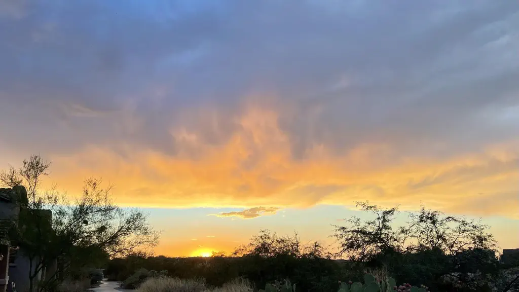 Clouds lit orange by setting sun with blue sky showing between cloud and sun