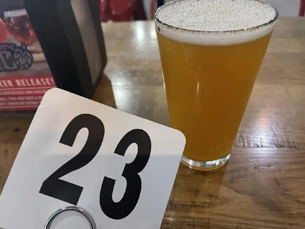 A waiting placard with the number 23, next to a pineapple-colored beer