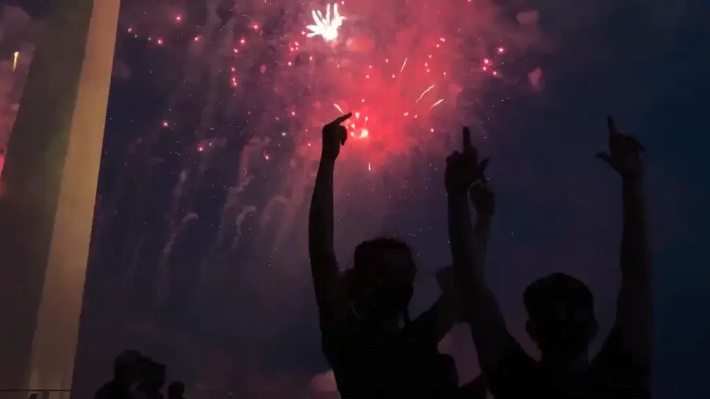 silhouetted protesters with middle fingers raised high, fireworks and washington monument in background
