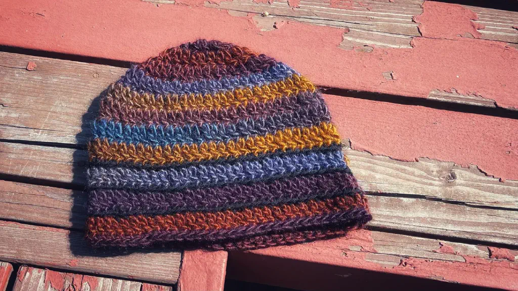 Multicolor striped crochet hat with blue yellow and sort of brownish red dominating