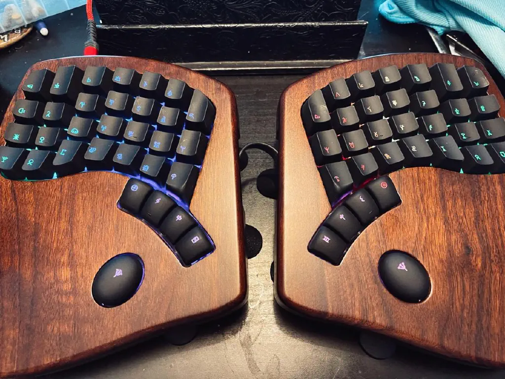Split ergonomic keyboard, case on and keycaps printed with Linear A characters