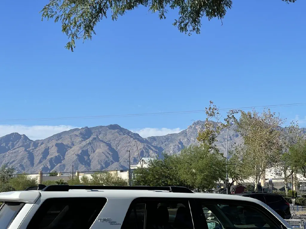 Brown mountains with blue sky overhead and a thin line of cloud behind.