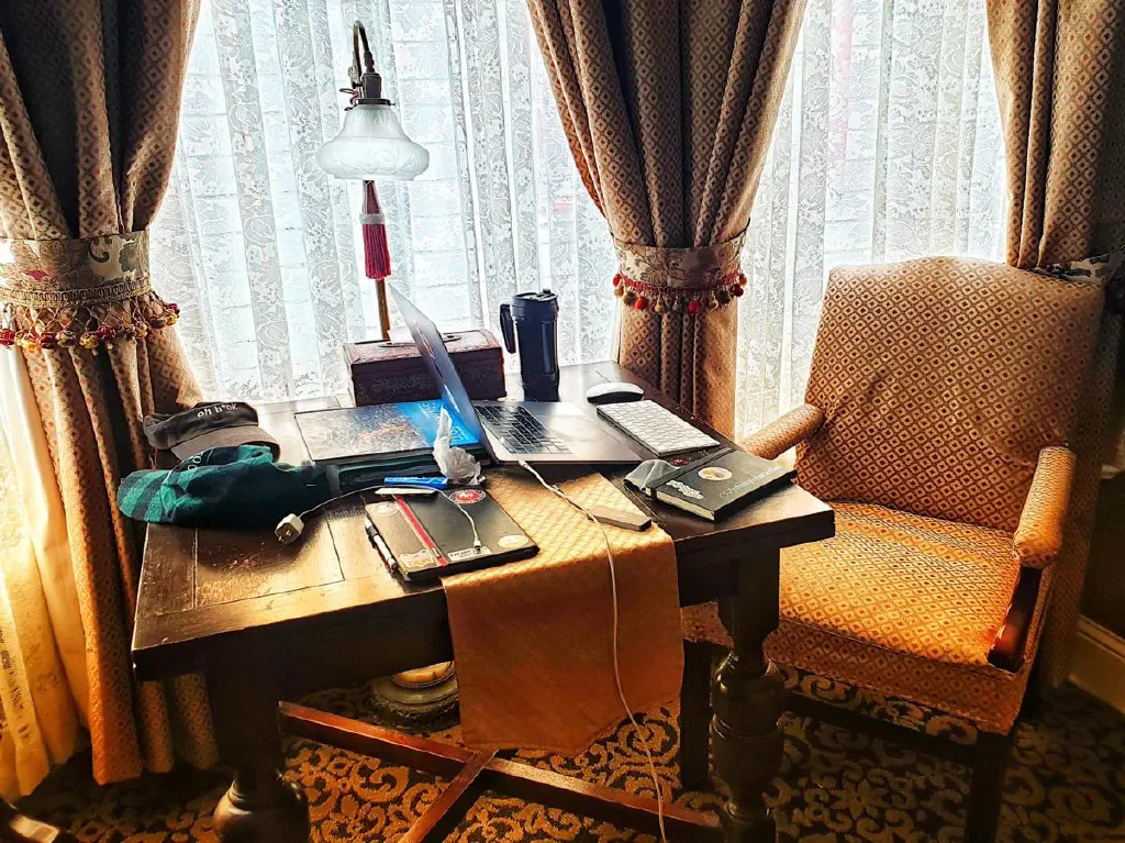 Laptop with peripherals from work on table in Victorian style hotel room
