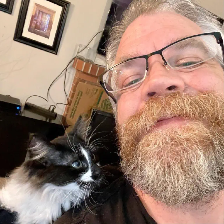 Nostril-dominant selfie of bearded dude, but the star is an adorable kitten sitting at his shoulder looking all cute. 