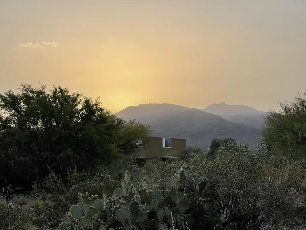 Sun rising behind a desert mountain, shrouded by brown haze