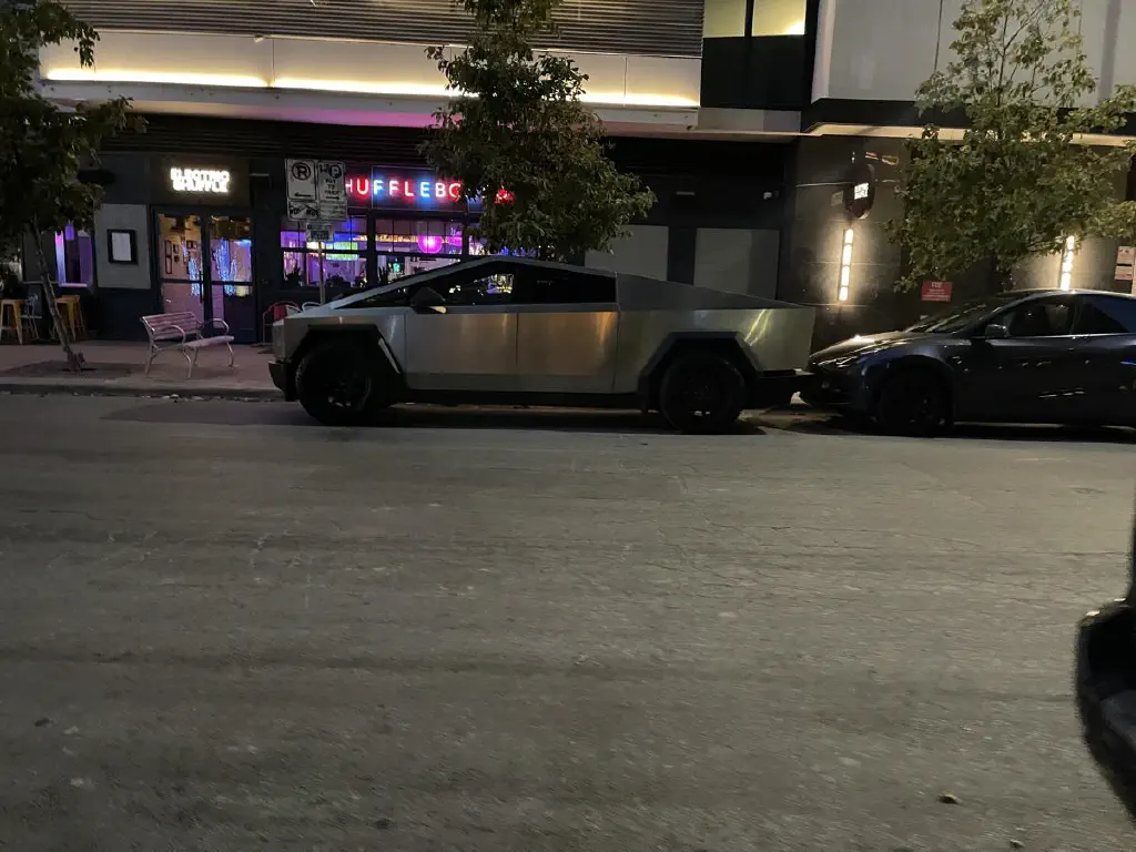 A Tesla cybertruck in street parking, next to a shuffleboard place.