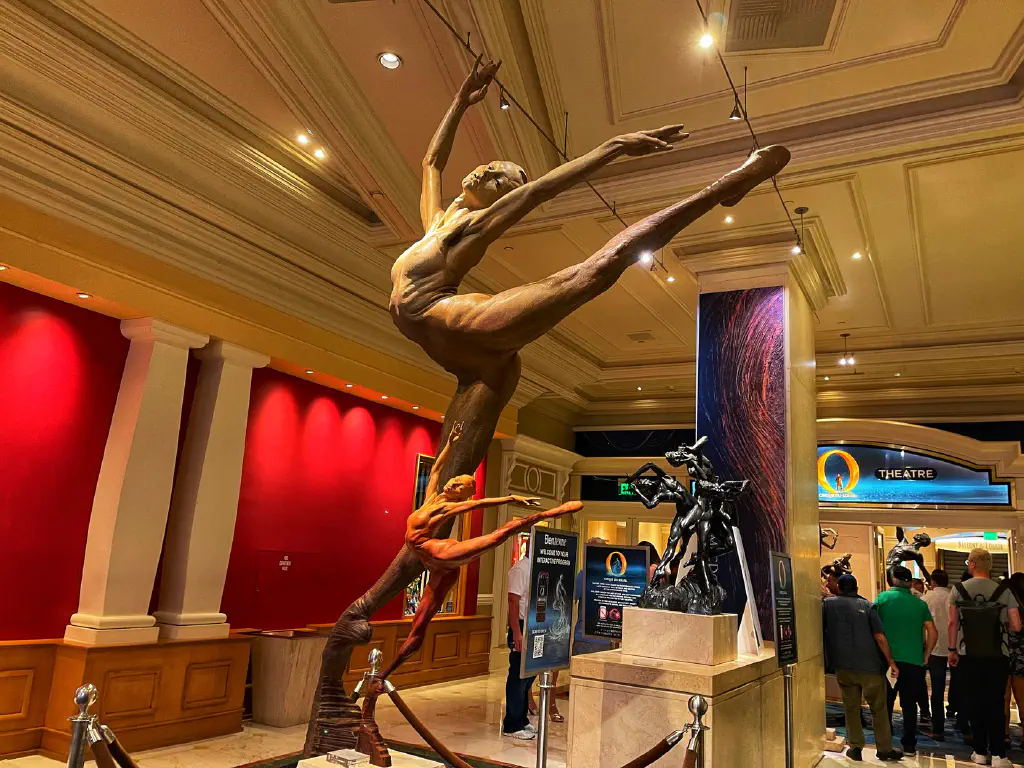 Bronze statue of female dancer in dynamic pose, with smaller version of same statue