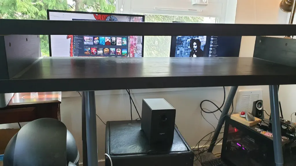 Monitors on windowsill behind partially disassembled desk