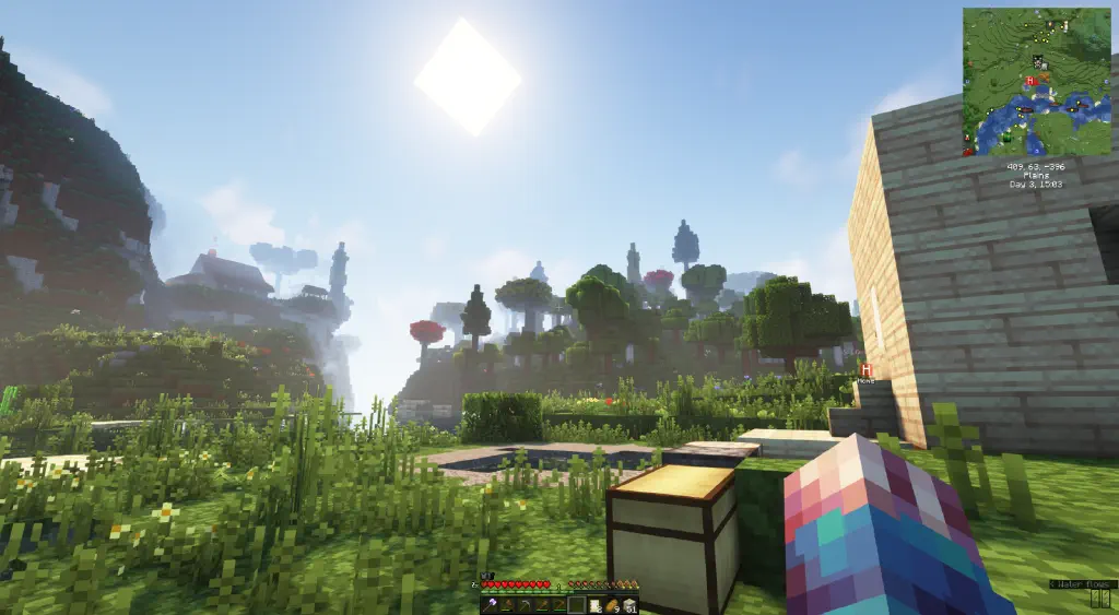 On top of a hill in the distance sits an attractive house with smoke coming out of a chimney and lovely trim on its roof. In the foreground is a classic Minecraft monotone starter cube house.