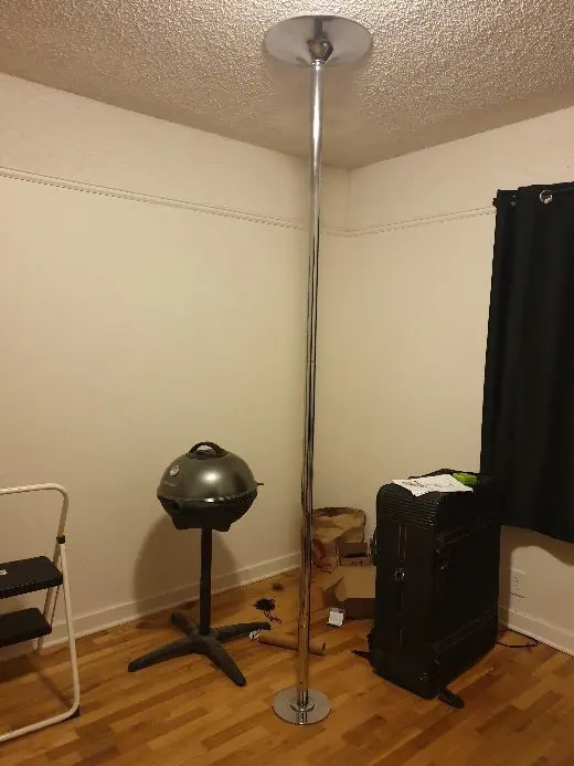 dance pole mounted in a cluttered room
