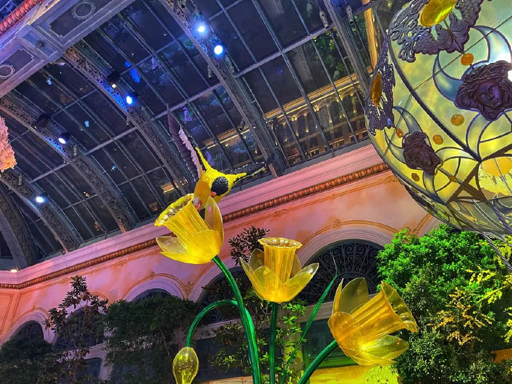 Giant songbird sculpture flying over giant plastic daffodils