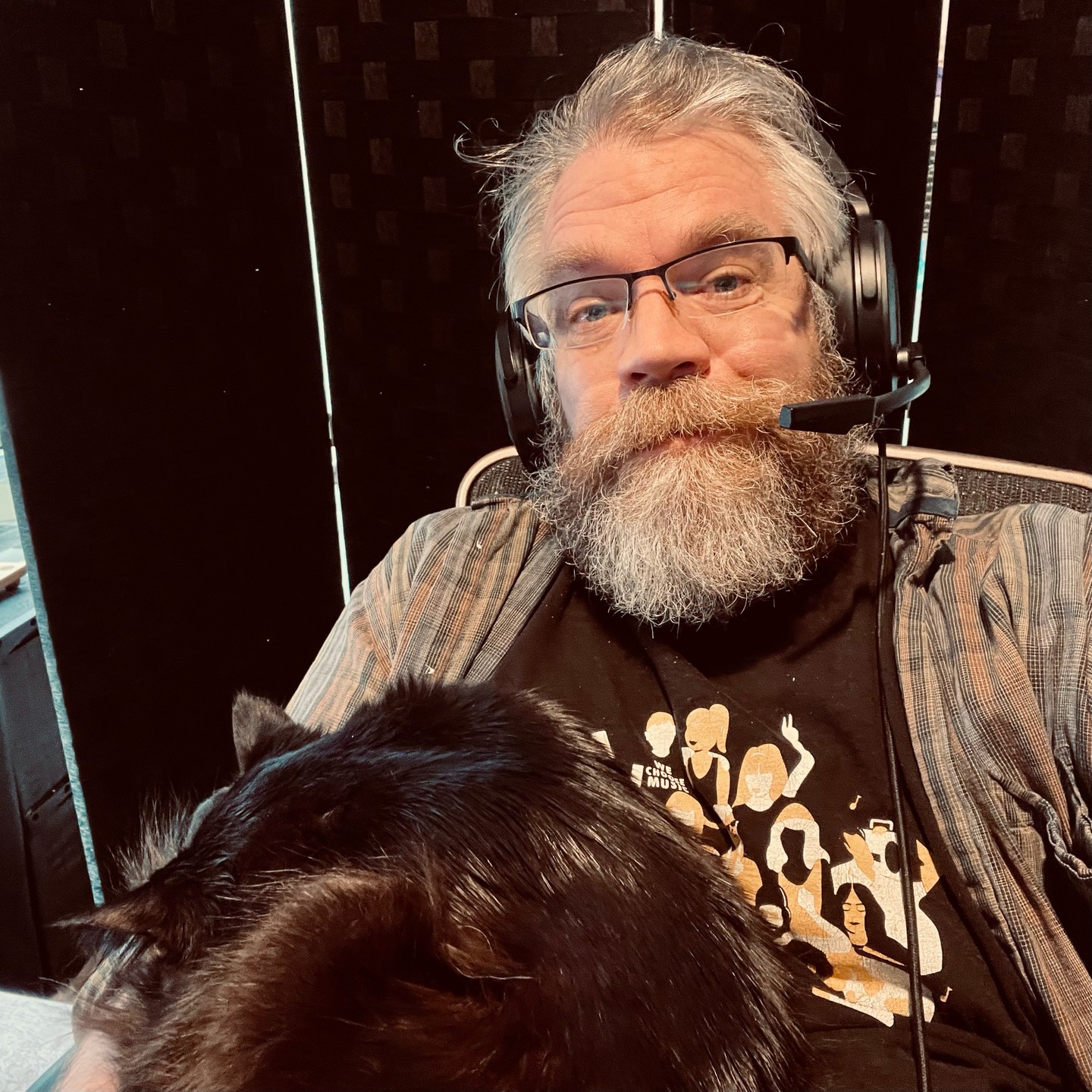 Selfie of beardy dude wearing headset while cat naps in his arm