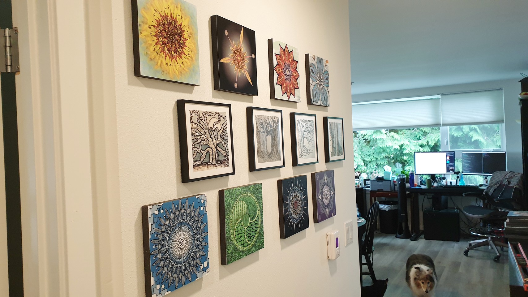 Wall decorated with tiles, each tile printed with one of our drawings; small dog walking in background