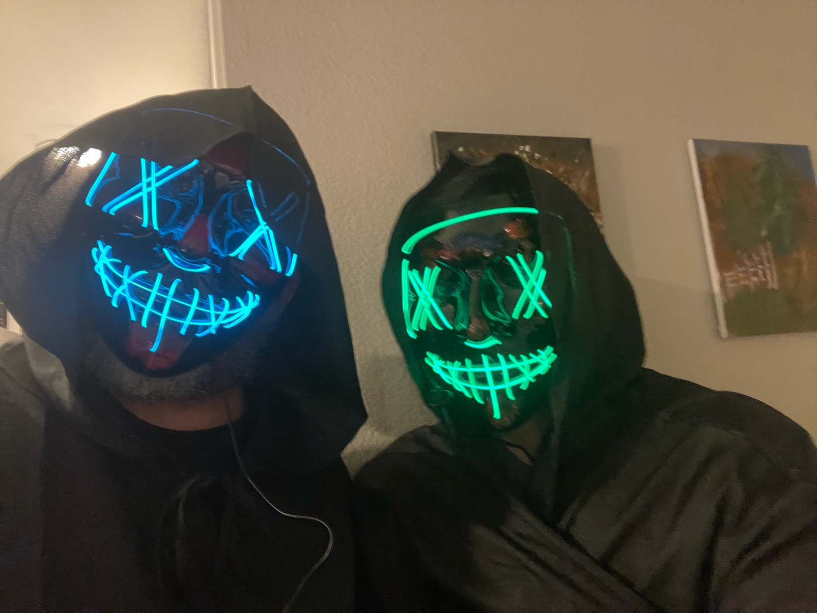 Selfie of two people in black robes and LED-lit masks. 