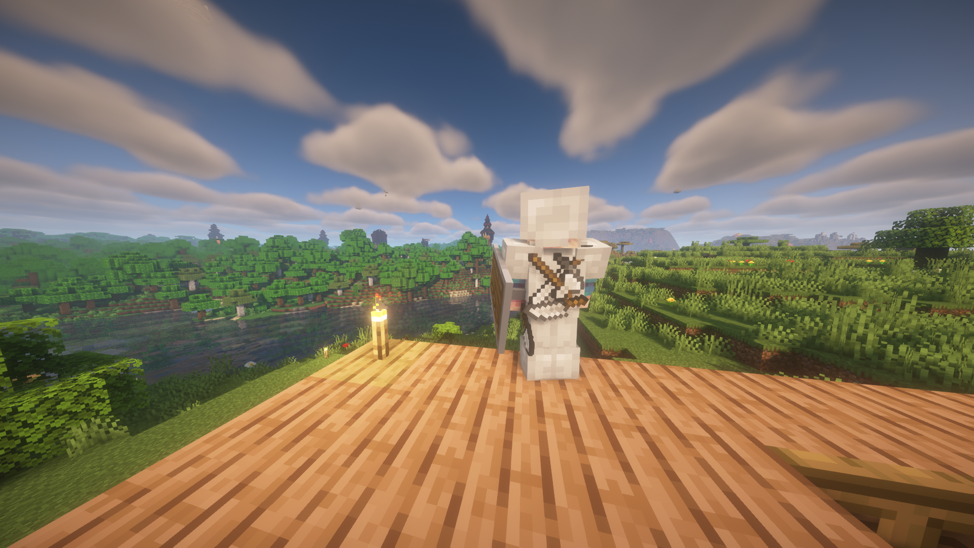 View over shoulder of iron-equipped player character, looking from rooftop at woods and towers in the distance.