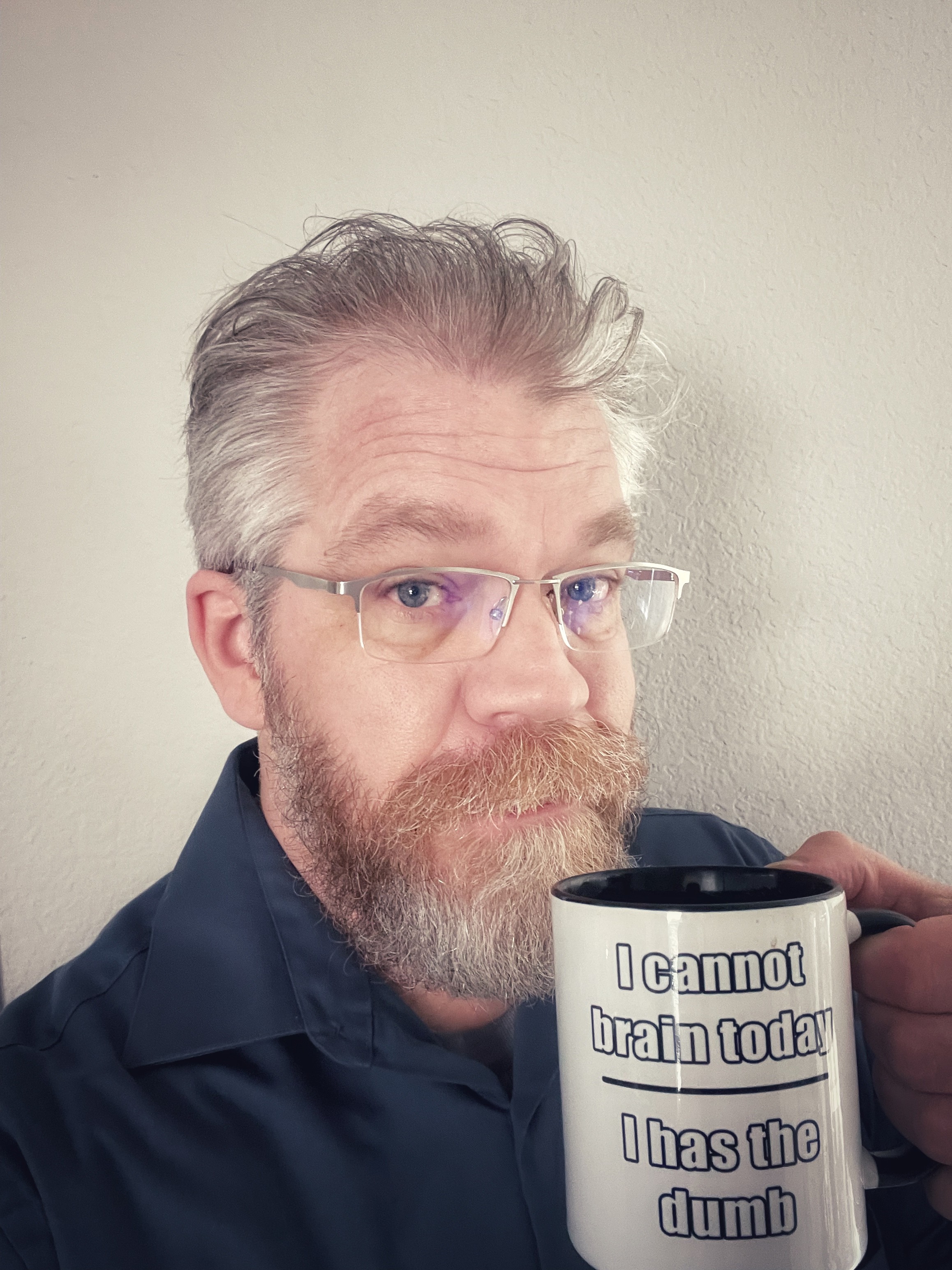 Neatly trimmed beardy dude in glasses holds a coffee cup with text “I cannot brain today — I has the dumb”