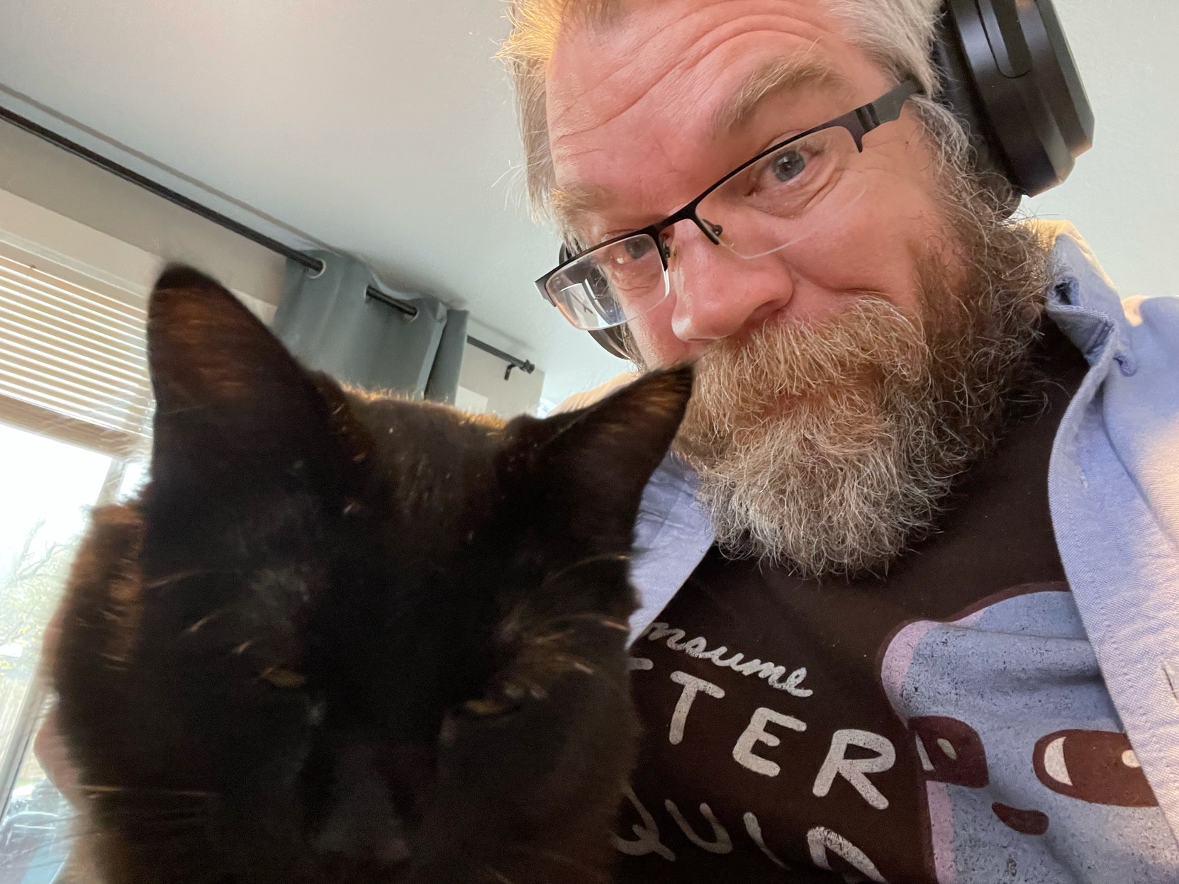 Selfie of beardy dude happily scritching black kitty