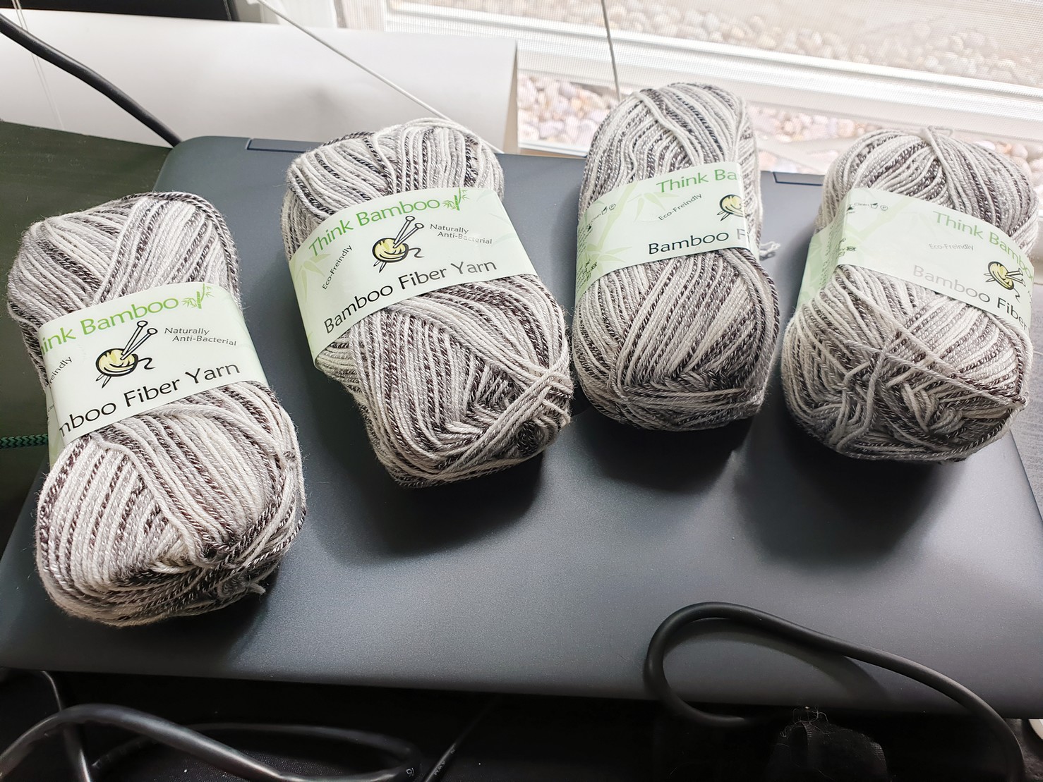 Four skeins of Think Bamboo brand sock yarn, multicolored in warm greys