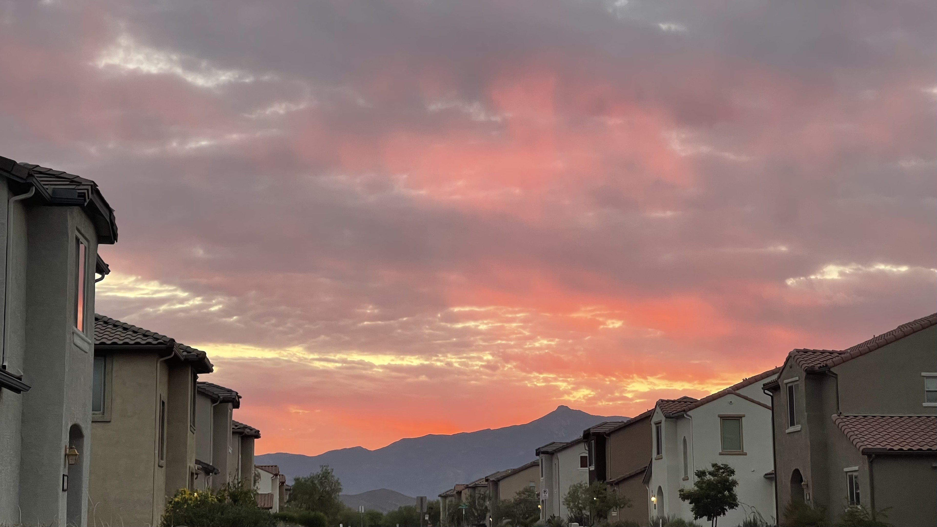 Clouds over a mountain, lit up orange and violet by the sunrise. 
