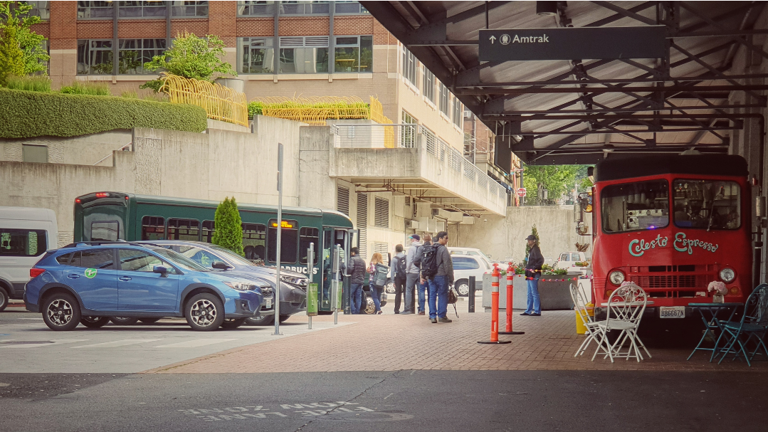 line of people getting onto bus at King Street Station, one looking back towards red Celeste Espresso coffee truck