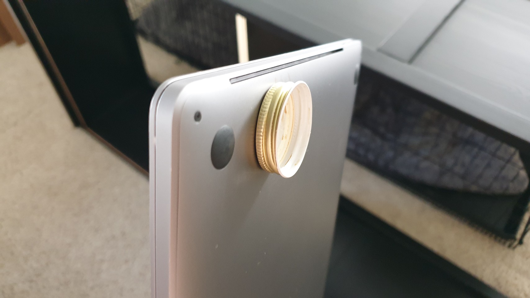 Bottle cap magnetically attached to bottom of MacBook pro